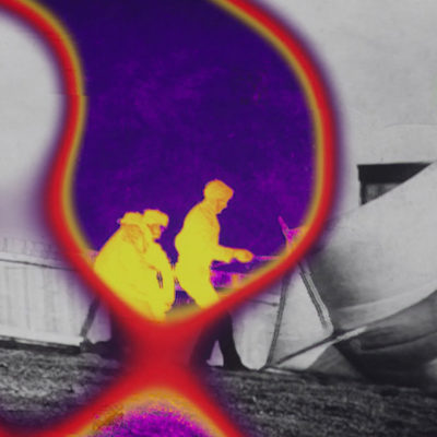 A black and white image with a thermographic, brightly coloured area in the center, where a group of three figures is visible.